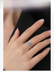 Close-up of S925 silver ring featuring oval blue zircon and pavé diamonds on finger