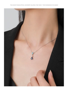 Detail of blue teardrop pendant necklace worn by a model in black attire