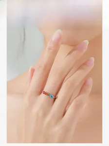 Close-up of a silver ring with rainbow zircon stones worn on a model's finger