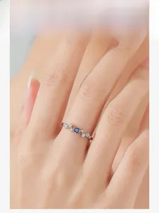 Detailed view of wave design silver ring with blue sapphire worn on a finger