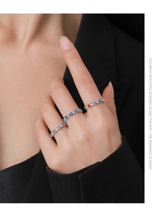 Macro detail of three silver rings with colorful heart-shaped stones on model finger