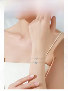 Detail of S925 silver double-layered bracelets with star and blue gem charms on wrist