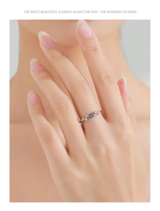 Detail of S925 sterling silver wave ring featuring a blue sapphire on a finger