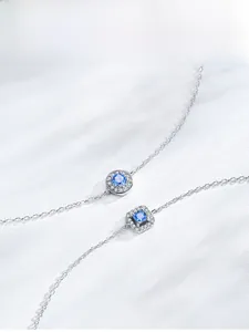 Detailed view of silver bracelets with blue stone pendants and small diamond borders