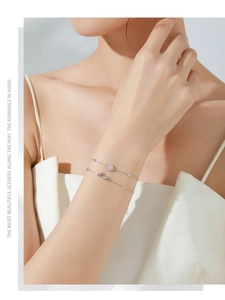 Detail of silver double-layered bracelet with pink square gem and Love lettering