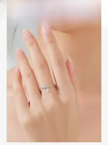 Detailed view of an S925 silver ring with small diamonds and a round dangling pendant