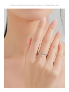 Detail of S925 silver ring with small diamonds and a dangling round charm on a finger