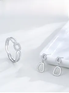 Detail of silver jewelry set with double-layered hollow ring and zircon earrings on a tray