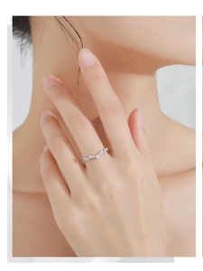 Macro detail of a silver V-shaped wave ring with cubic zirconia stones worn by a model
