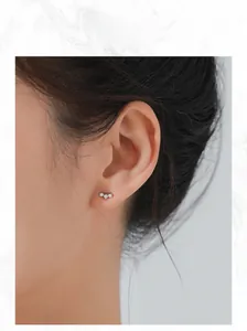 Close-up of S925 sterling silver curved earrings with three sparkling zircons on ear