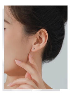 Close-up of small S925 sterling silver triangle stud earrings worn on a model's ear