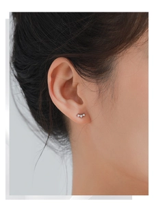Close-up of three-stone silver geometric triangle stud earrings worn on the earlobe