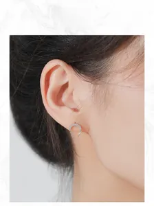 Macro shot of silver C-shaped chain drop earrings with sparkling white crystals on model