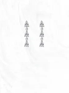 Detailed close-up of triple teardrop zircon stones hanging from a silver earrings