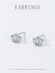 Gros plan sur les boucles d'oreilles couronne en argent avec trois zircons rectangulaires