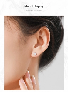 Gros plan d'une boucle d'oreille couronne en argent avec zircone portée par un modèle