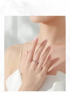Close-up of a silver adjustable tassel ring with charms worn on a model hand