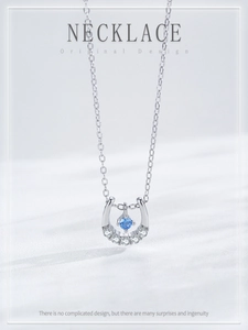 Macro detail of horse-shoe pendant featuring blue gemstone and white cubic zirconia