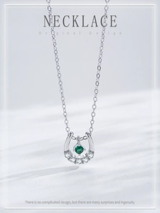 Macro shot of S925 silver horseshoe necklace with emerald gemstone and sparkling diamonds