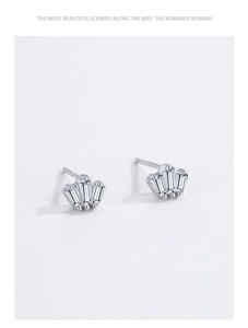 Gros plan sur les boucles d'oreilles couronne en argent avec trois zircons baguettes