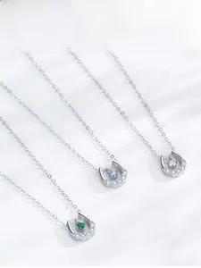 Macro detail of U-shaped silver horseshoe pendants with green, blue, and yellow zircons