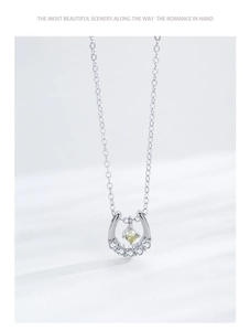 Macro detail of silver horseshoe pendant with yellow gemstone and white pavé crystals