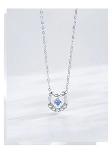 Macro shot of S925 silver horseshoe necklace with blue gemstone and pavé set zircons