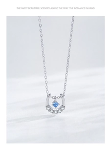 Macro d'un pendentif fer à cheval avec pierre bleue claire et détails en zircons fins