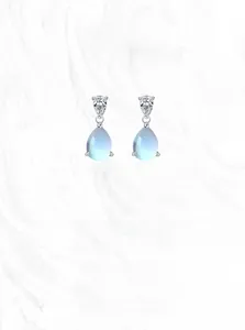 Détail macro de boucles d'oreilles goutte en argent avec pierres bleues facettées