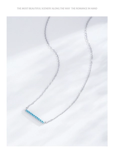 Macro detail of S925 sterling silver necklace with turquoise geometric pendant on white surface