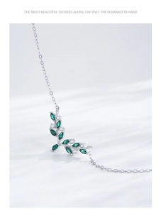 Macro shot of 925 silver leaf pendant with emerald green and white cubic zirconia stones