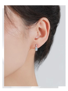 Gros plan de boucles d'oreilles clous en argent S925 et pierre de lune portées