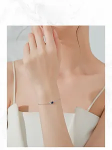 Close-up of minimalist S925 silver bracelet featuring pear-shaped and blue gemstones on wrist