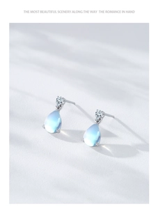 Détail macro de boucles d'oreilles goutte en argent S925 et pierre de lune sur texture