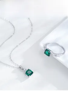 Close-up of S925 sterling silver square emerald ring and necklace set with side diamonds