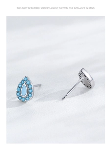 Vista detallada de pendientes de plata en forma de gota con turquesa azulada