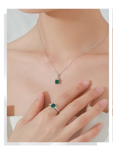 Close-up of S925 sterling silver set featuring emerald cut green gemstone necklace and ring