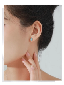 Primer plano de pendientes de plata con turquesas en forma de gota en una modelo