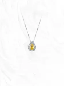 Macro shot of silver pear-cut yellow gemstone necklace with sparkling halo detail