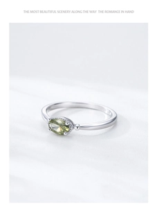 Macro detail of S925 sterling silver ring with oval olive green gemstone in claw setting