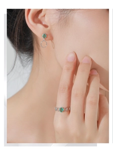 Detail shot of the oval green gemstone ring and matching earrings on a model