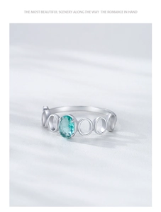 Macro shot of silver镂空 ring band with oval mint green gemstone on white surface