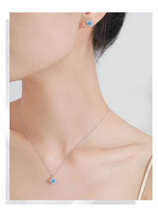 Gros plan d'un ensemble collier et boucles d'oreilles en argent S925 et aigue-marine