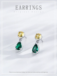Detail of S925 silver earrings with round yellow and pear-shaped green zircon stones