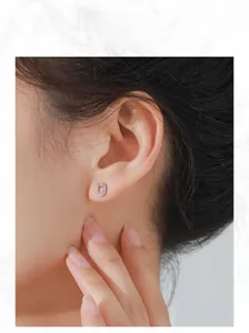 Close-up of elegant pink oval Morganite stud earring with halo design on a model's ear