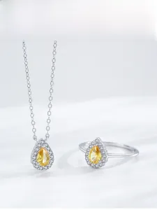 Macro view of pear cut yellow diamond necklace and ring set in polished silver