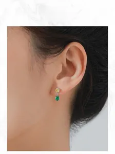 Close-up of S925 silver stud earrings with yellow round and green pear-cut stones