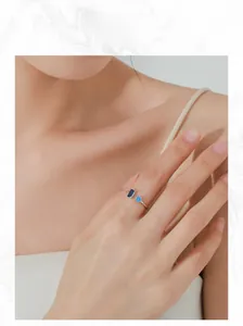 Gros plan d'une bague ouverte en argent S925 avec zircons bleus sur la main d'un mannequin