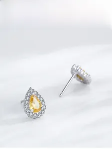 Vue macro de boucles d'oreilles poires en zircon jaune avec monture halo argentée