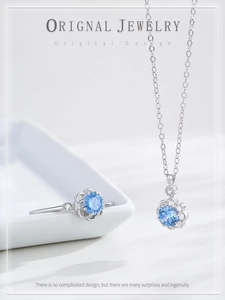Detail of S925 silver flower ring and necklace set with light blue gemstone in ceramic tray